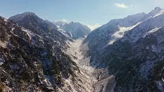 Majestic snow-covered winter mountains under clear blue sky, drone view