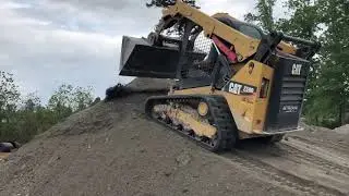Cat 259D skid steer pushing gravel