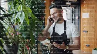 Slow motion of flower shop manager talking on mobile phone and using tablet