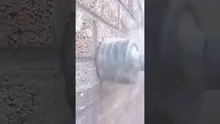 drilling a round hole automatically using a silver drill bit into a brown brick wall in an outdoor