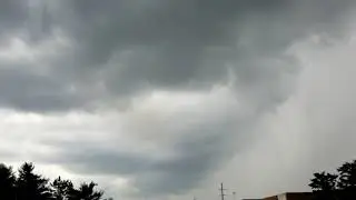 Dramatic time lapse of storm clouds blowing in then rain on window