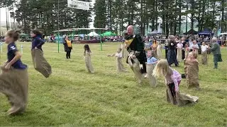 Drum Major Derek Dean taking part in Children's Sack Race during 2023 Tomintoul Highland Games