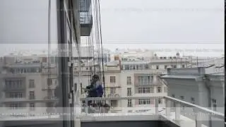 Rope access specialists cleaning facade windows. City buildings in the background