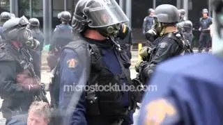 Riot officers stand by with automatic fire weapon and gas masks