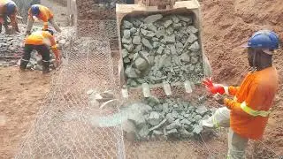 Escavadeira levando rachão para gabião 