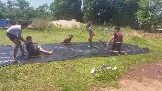 Crianças brincando de escorregar na lona com sabão...