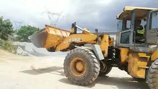 Old Wheelloader is loading chippings and sand into concrete batching plant bins for concrete product