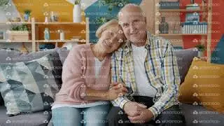 Portrait of elderly man and woman happy couple sitting on sofa at home smiling