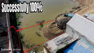 Dump truck unloading stone into water & Mini dozer pushing to building the fence