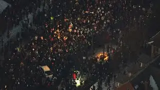 Thousands gather for a vigil at the scene where a woman was shot and killed by ICE agent
