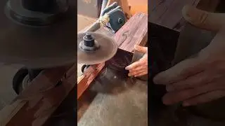 cutting a thick piece of dark wood with a large circular saw blade to create a smooth flat surface