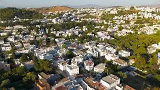 Bodrum, Turkey. Aerial drone flight over traditional white houses with flat roofs and green trees...