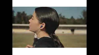 woman putting on headphones in the park | Tech Gali