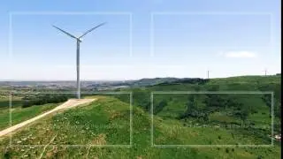 Wind power plants on a green hills in Portugal aerial view