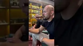 Andrew tate enjoying a cigar with coffee in a cigar lounge