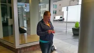 A woman opens a pack of cigarettes and throws the plastic wrapping on the ground.