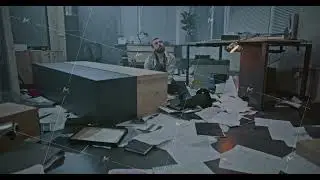 Dolly shot of depressed office worker sitting on the floor in destroyed office room