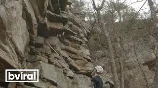 Climber, wearing a helmet, gets hit on the head with a rock.