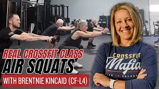 Тренер CrossFit 4-го уровня обучает воздушным приседаниям на групповых занятиях.