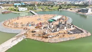 Trucks load large rocks into the lake and excavators dig up the rocks to make a footpath