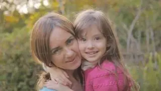 Mom and daughter in nature laugh and kiss