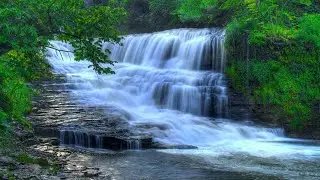 A serene waterfall flowing gently over layered rocks into a clear stream best music sound, relaxing