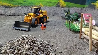 Rc loader loading gravel into rc dump truck at quarry site.