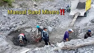 Manual sand miner collects black sand into truck bed