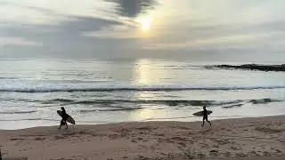 Dee Why Beach after sunrise. Surfers. Swimmers. Sunlight on the water. 