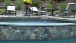 magnificient poolscape with inviting splash pool, stone hot tub, outdoor kitchen and more