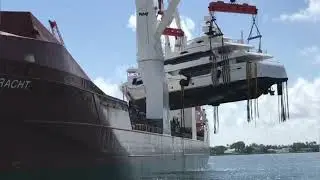 Loading a large yacht onto a cargo ship at the seaport.