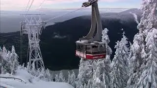 Static shot of Sky Ride Gondola travelling up Grouse Mountain with North Vancouver and ocean