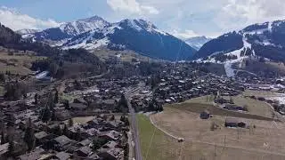 Aerial view capturing Gstaad village surrounded by snow covered Swiss Alps, highlighting mountain
