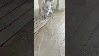 Leveling wet concrete surface using a long screed tool for smooth and even floor finish