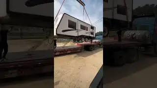 How does the crane lift the RV onto the flatbed truck