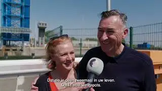 Nieuwsgierigen kijken naar het transport van het eerste tunneldeel in de haven van Zeebrugge