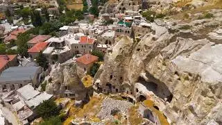 Urgup, Nevsehir, Turkey. Detailed drone flight along rocky cliff with modern cave hotels and aban...