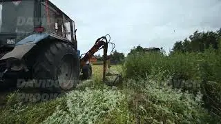 Tractor mowing green field, performing routine agricultural land maintenance task
