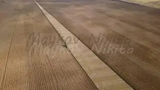 The tractor plows a field with fertilizers. Autumn, Russia, From Dron, Departure of the camera