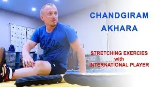 Wrestlers doing stretching exercises with International player at Chandgiram Akhara