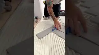 applying and spreading the grey floor tile adhesive using a metal square notched trowel tool #shorts