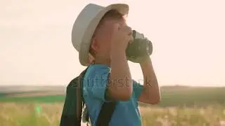 Cute little kid is holding vintage camera and taking pictures of nature. Child dreams of traveling,