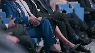 Audience seated during a business conference holding mobile devices and focused