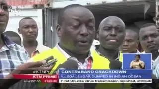 Customs officials empty containers of contraband sugar and rice into the Indian Ocean