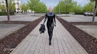 Caribig in black vinyl catsuit, underbust corset, leather jacket and high heels parking walk