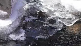 Stock Video - Close up of water moving under the ice in a creek