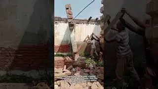 Manual Demolition: Two Men Topple a Brick Pillar