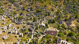 Kayakoy, Turkey. Wide aerial drone view of ancient Karmylassos ghost town ruins on mountain slope...