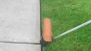 Man Edges Sidewalk Grass Neatly Using String Trimmer - 1131958