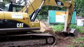 Caterpillar 324D crawler excavator digging topsoil at construction site